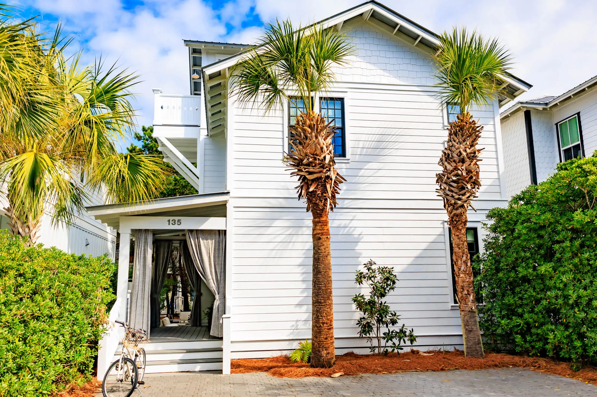 A two-story coastal home featuring pristine white lap siding and dark-trimmed windows, showcasing a flawless exterior finish by Grayton Painting.