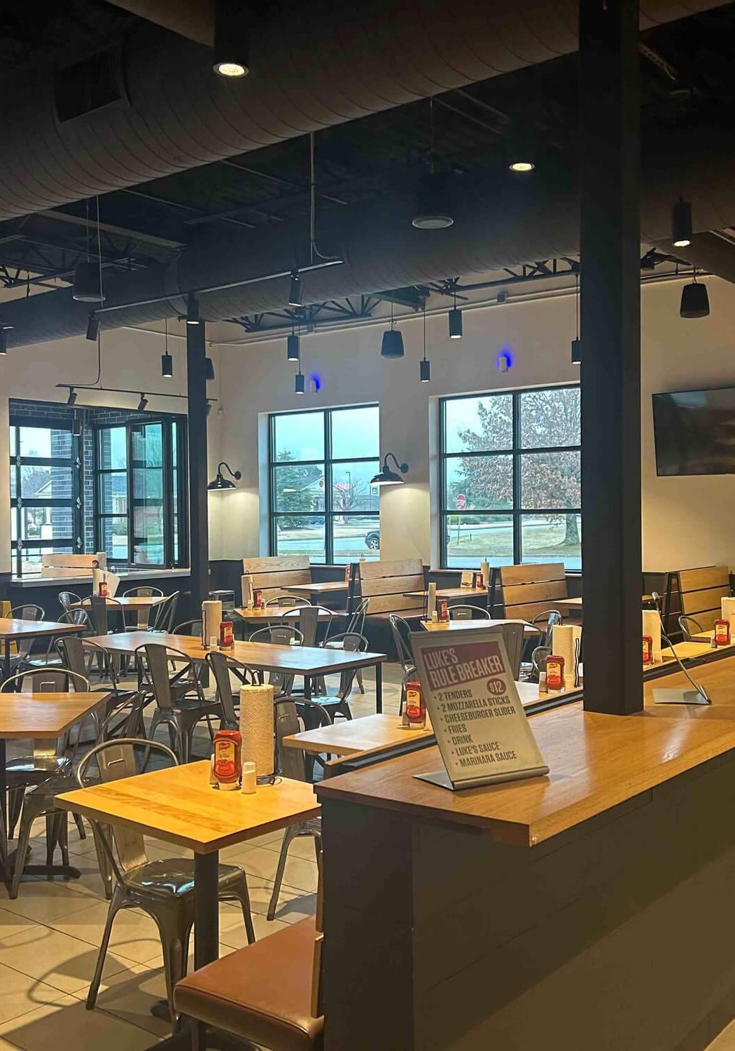 Clean, modern restaurant interior with freshly painted walls, open seating layout, wood tables, and exposed ceiling details.